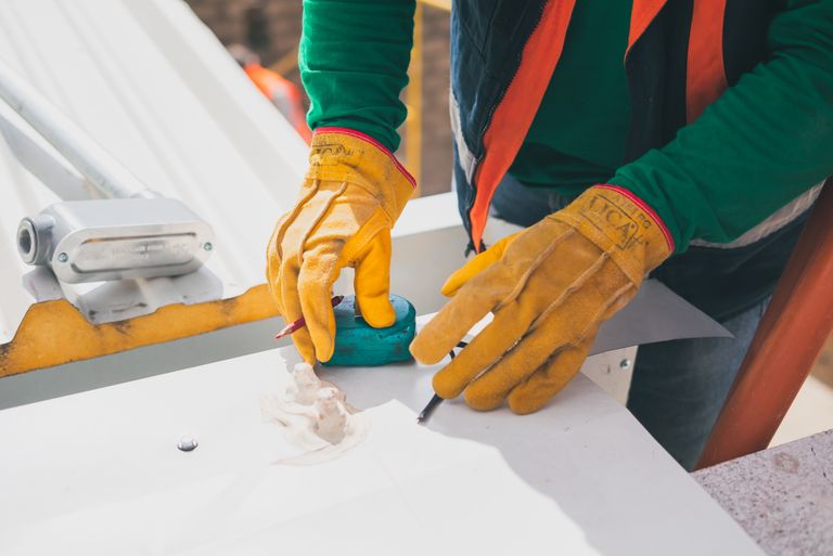 Person in attic measuring roof rafter angle with a level and tape measure