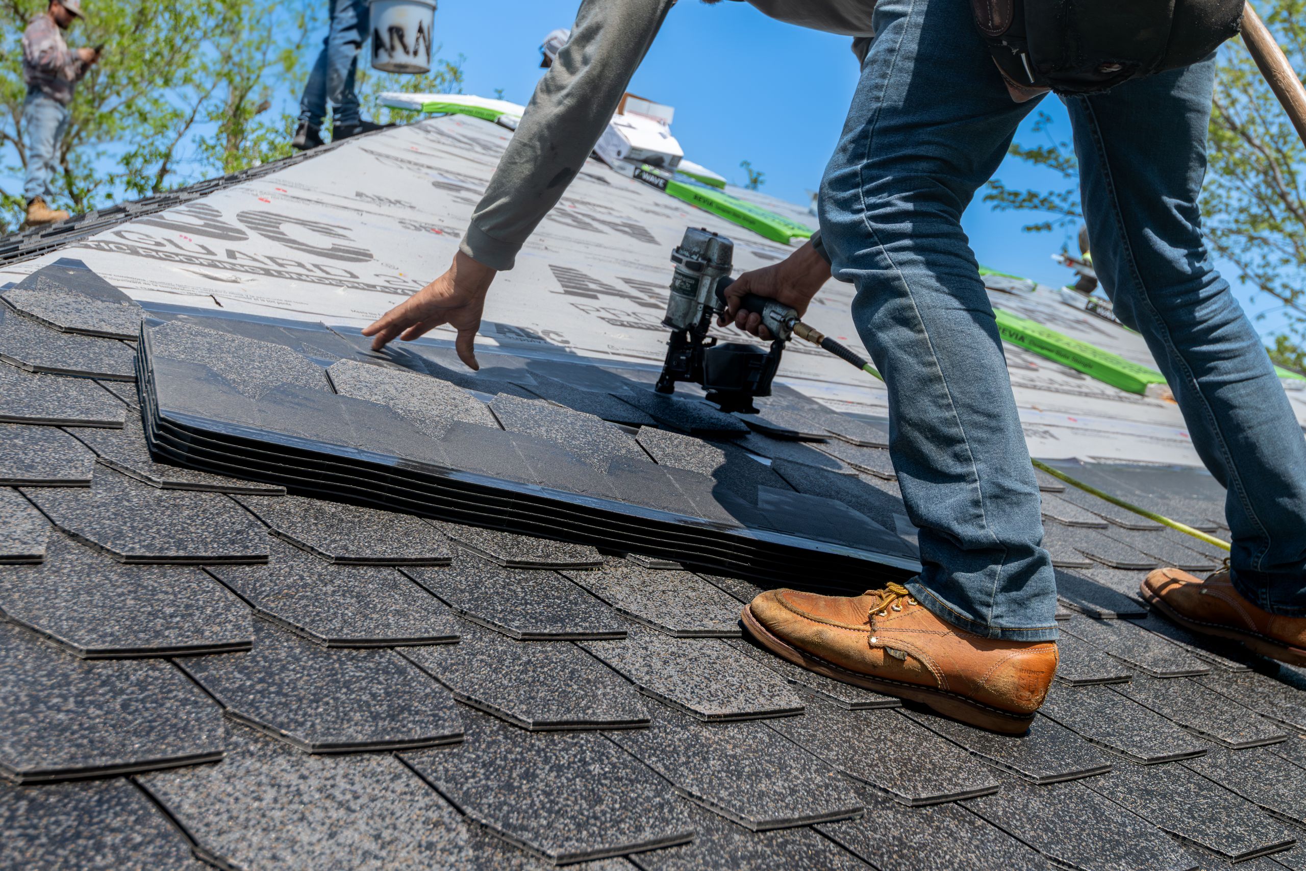 Roofing crew installing new architectural asphalt shingles on a residential home