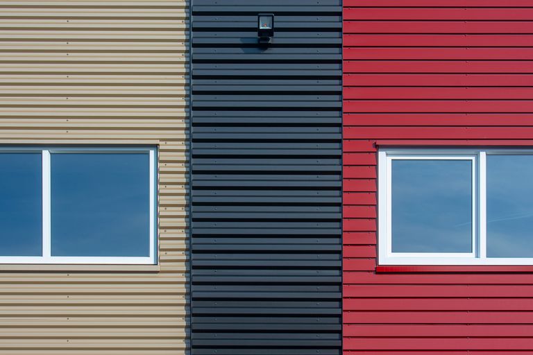Close-up of a modern facade featuring colorful corrugated panels with windows.