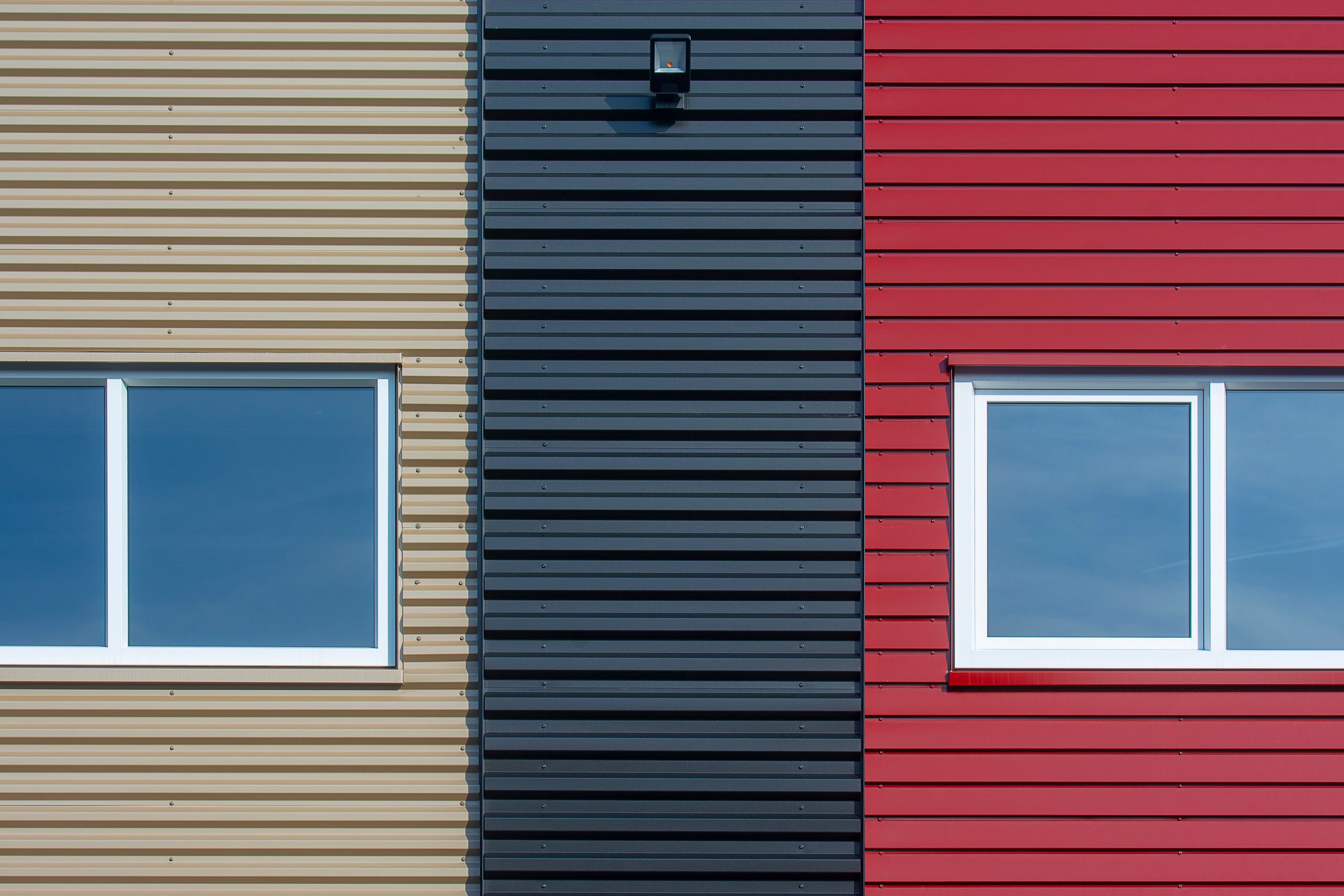Close-up of a modern facade featuring colorful corrugated panels with windows.